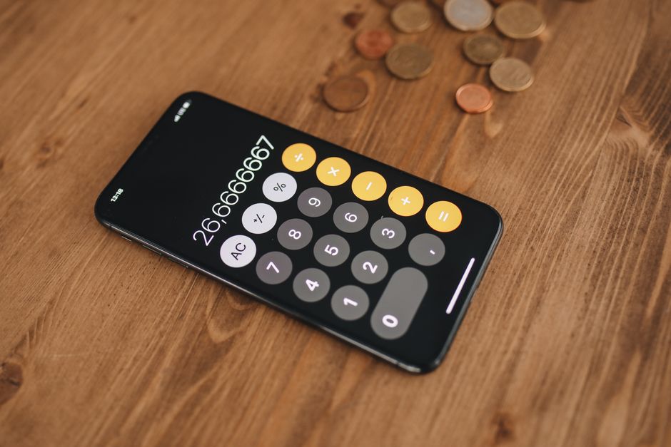 Akıllı telefon ekranında bütçe uygulaması açıkken harcama planı yapan kişi