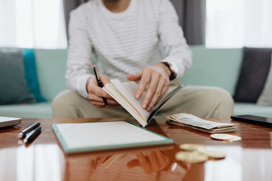 Bir bireyin aylık bütçesini dikkatlice incelediği an ve masada bütçe dokümanları bulunmaktadır.
